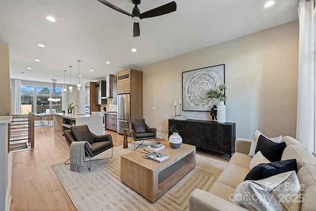 living room featuring ceiling fan, sink, and light hardwood / wood-style floors