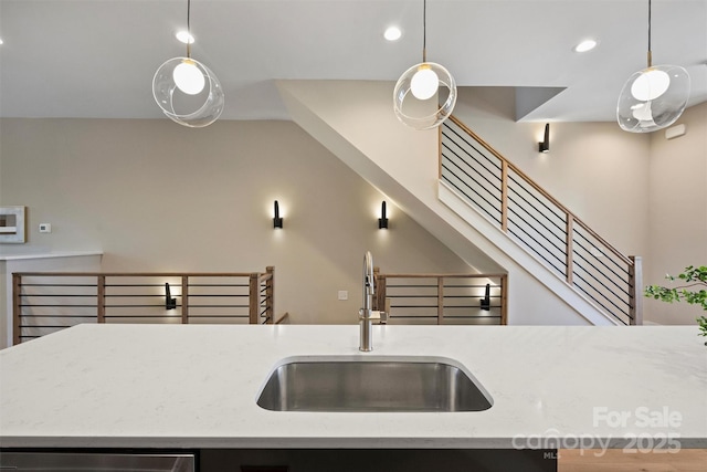 kitchen with light stone counters, sink, and pendant lighting