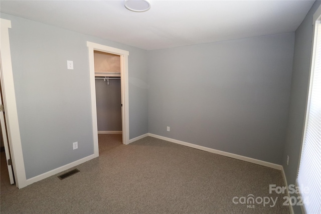 unfurnished bedroom featuring a closet, a spacious closet, and carpet