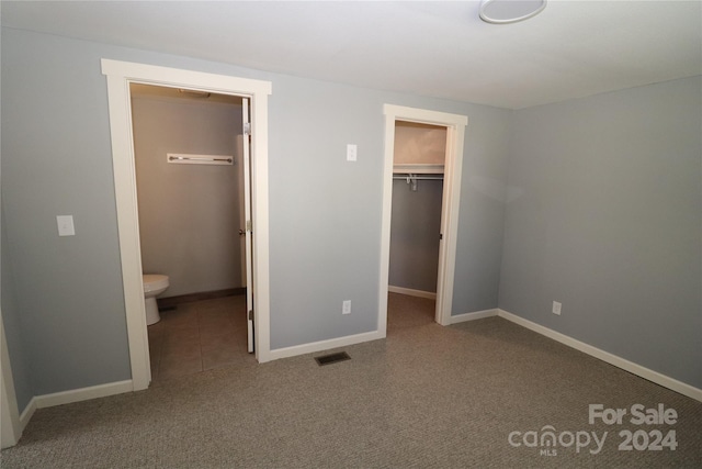 unfurnished bedroom with a closet, carpet flooring, and a spacious closet