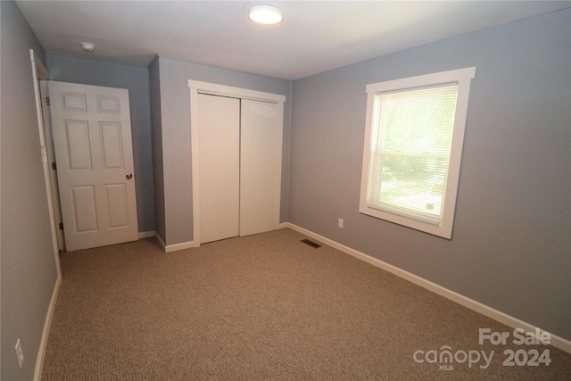 unfurnished bedroom with a closet and light colored carpet