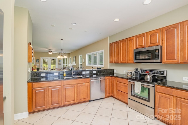 kitchen with hanging light fixtures, appliances with stainless steel finishes, sink, and dark stone countertops