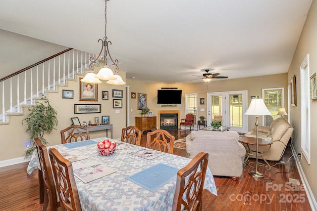 dining room with dark hardwood / wood-style flooring and ceiling fan with notable chandelier