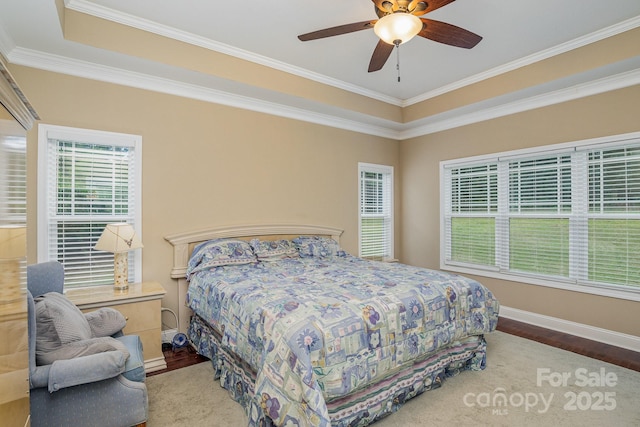 bedroom featuring ceiling fan, ornamental molding, a tray ceiling, and wood-type flooring