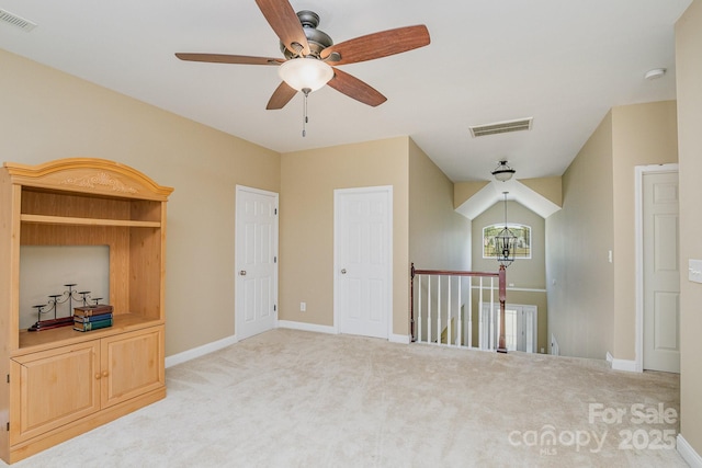 spare room with light carpet and ceiling fan with notable chandelier