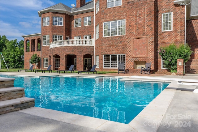 view of pool with a patio area and an outdoor brick fireplace