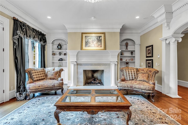 living room with ornate columns, a high end fireplace, wood-type flooring, and built in shelves