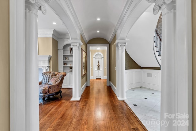 foyer entrance featuring lofted ceiling, crown molding, light hardwood / wood-style floors, and decorative columns