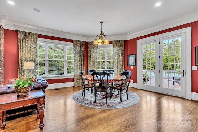 dining space featuring hardwood / wood-style floors, ornamental molding, and an inviting chandelier