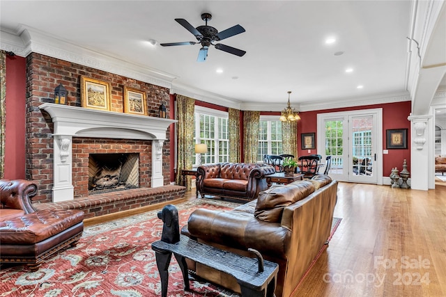 living room featuring a fireplace, light hardwood / wood-style floors, crown molding, and a healthy amount of sunlight