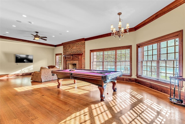 playroom with a fireplace, pool table, crown molding, light hardwood / wood-style flooring, and ceiling fan with notable chandelier