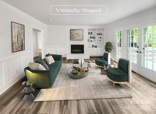 living room with built in shelves, a fireplace, ornamental molding, and hardwood / wood-style floors