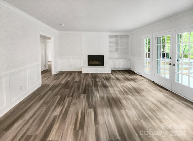 unfurnished living room featuring built in features, dark hardwood / wood-style flooring, french doors, and a fireplace