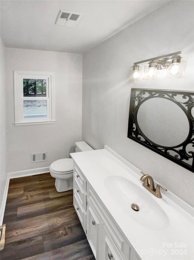 bathroom with toilet, vanity, and wood-type flooring
