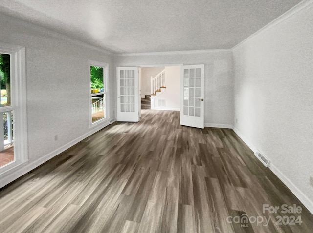 empty room featuring dark hardwood / wood-style floors, ornamental molding, and french doors