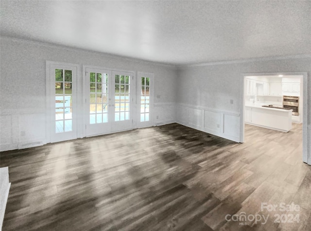 unfurnished living room featuring dark wood-type flooring, ornamental molding, and french doors