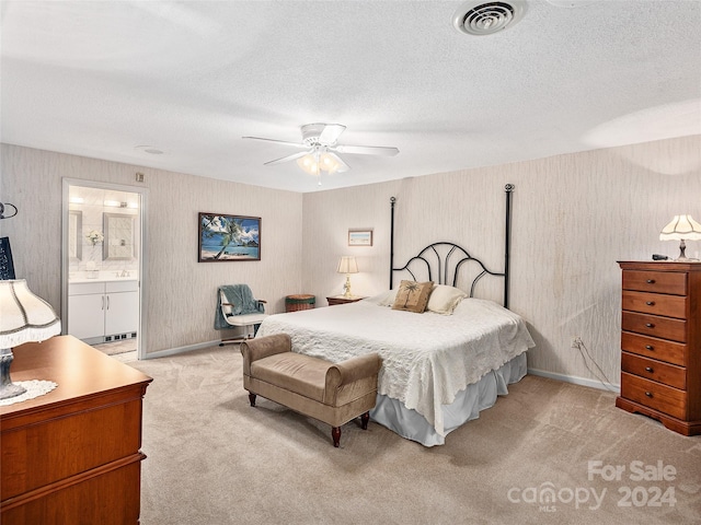 bedroom with ensuite bath, ceiling fan, light carpet, and a textured ceiling