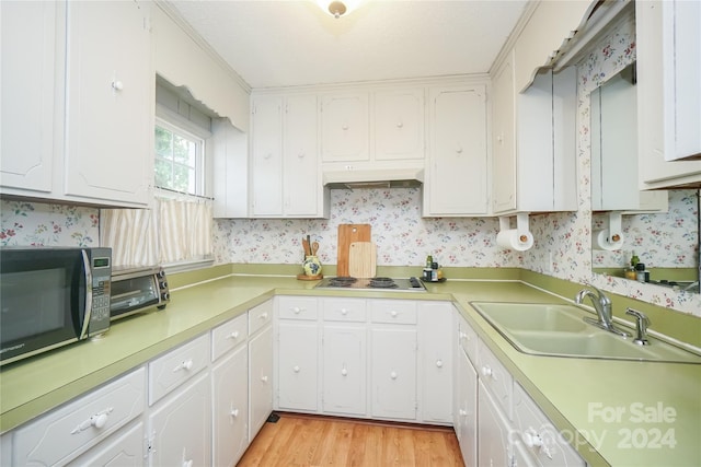 kitchen with light wood-type flooring, white stovetop, white cabinets, and sink