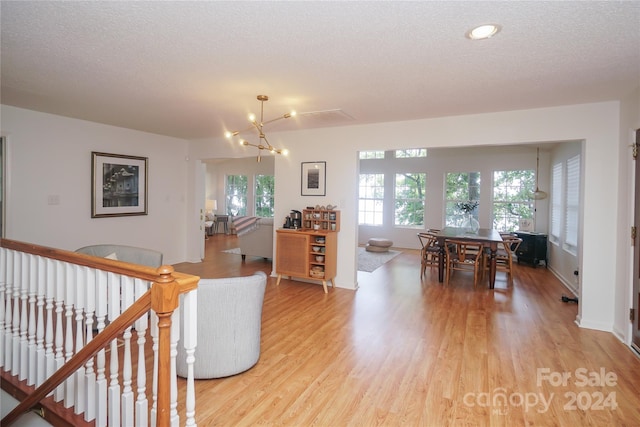 living room featuring a notable chandelier, a textured ceiling, and light hardwood / wood-style flooring