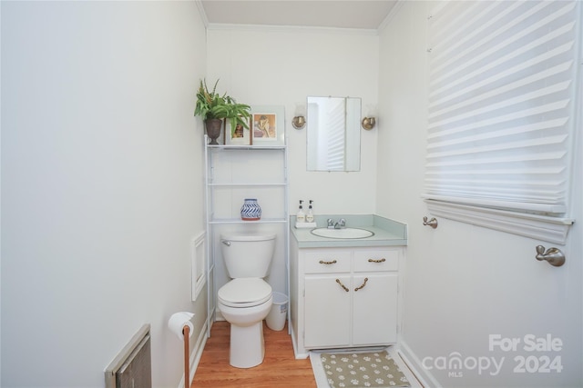 bathroom featuring toilet, vanity, hardwood / wood-style floors, radiator, and ornamental molding