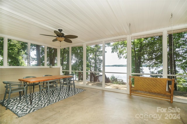 sunroom / solarium with ceiling fan and a water view