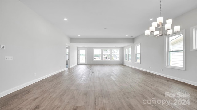 unfurnished living room with hardwood / wood-style floors and a chandelier