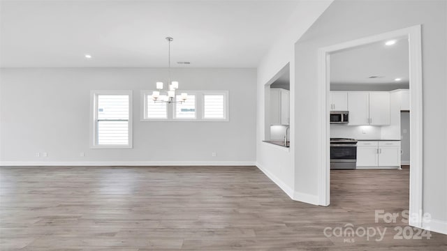 unfurnished dining area featuring a chandelier and light hardwood / wood-style floors