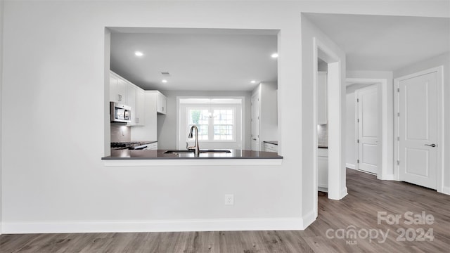 kitchen with tasteful backsplash, kitchen peninsula, white cabinetry, and sink