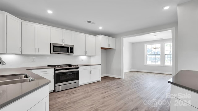 kitchen featuring white cabinetry, sink, light wood-type flooring, and appliances with stainless steel finishes