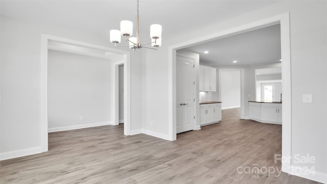 unfurnished dining area with light wood-type flooring and a chandelier