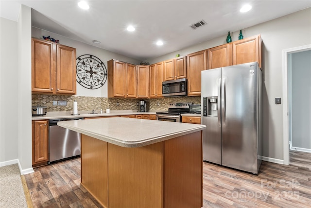 kitchen with tasteful backsplash, stainless steel appliances, light hardwood / wood-style flooring, a kitchen island, and a breakfast bar area