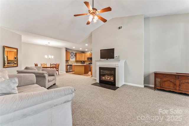 living room with ceiling fan with notable chandelier, light carpet, and vaulted ceiling