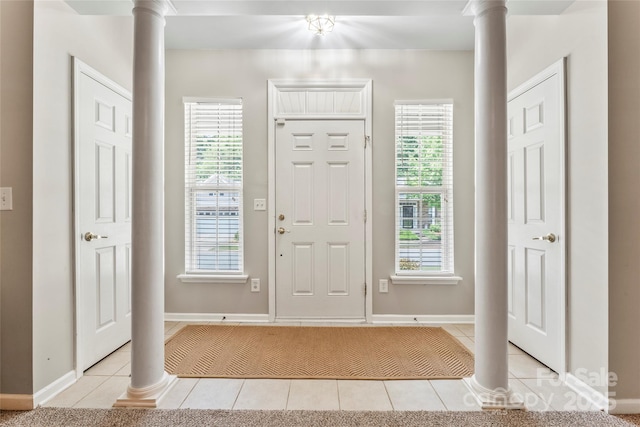 foyer featuring light tile patterned flooring and ornate columns