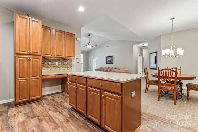 kitchen with tasteful backsplash, ceiling fan with notable chandelier, dark wood-type flooring, pendant lighting, and lofted ceiling