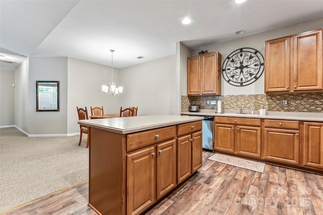 kitchen featuring wood-type flooring, a notable chandelier, dishwasher, a kitchen island, and hanging light fixtures