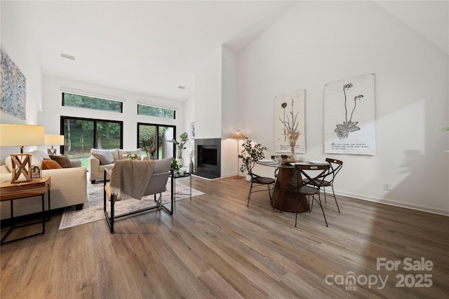 living room featuring a multi sided fireplace, a towering ceiling, and hardwood / wood-style flooring