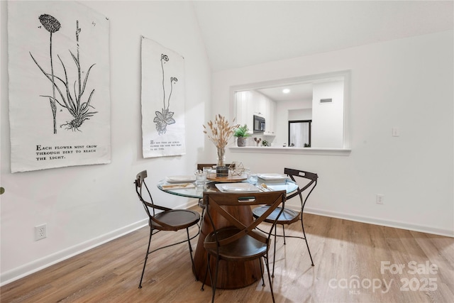 dining area featuring vaulted ceiling and hardwood / wood-style flooring