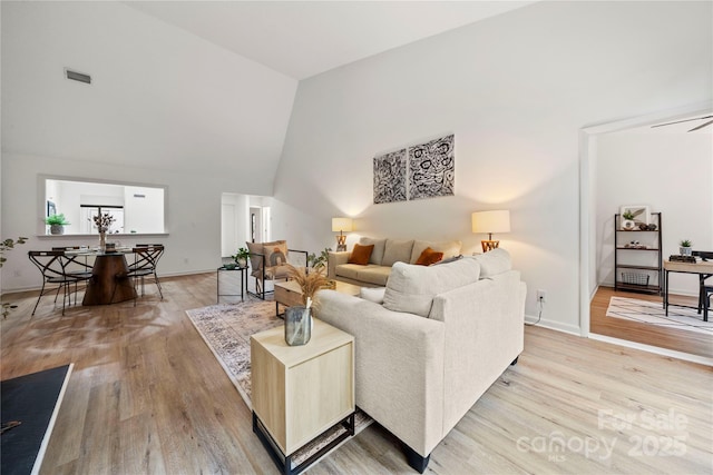 living room with ceiling fan, light hardwood / wood-style flooring, and high vaulted ceiling