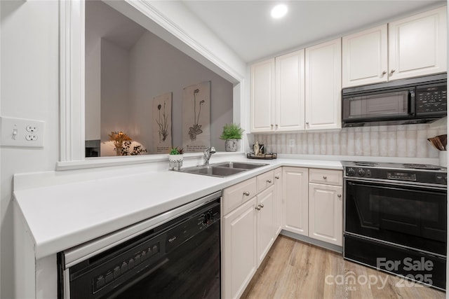 kitchen with light wood-type flooring, tasteful backsplash, sink, black appliances, and white cabinetry