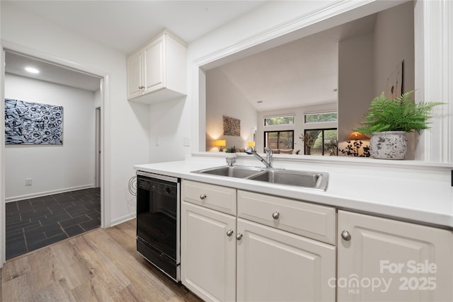 kitchen with dishwasher, white cabinetry, sink, and light hardwood / wood-style flooring