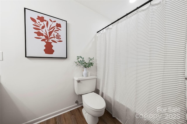 bathroom with hardwood / wood-style flooring, toilet, and walk in shower