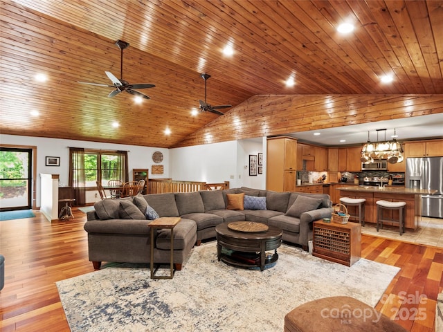 living room with ceiling fan with notable chandelier, wood ceiling, and light hardwood / wood-style flooring