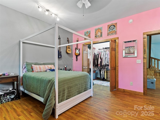 bedroom featuring hardwood / wood-style floors, a closet, track lighting, and ceiling fan