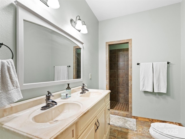 bathroom featuring a tile shower, vanity, and toilet