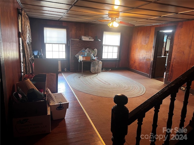 interior space featuring ceiling fan, wooden walls, and hardwood / wood-style floors