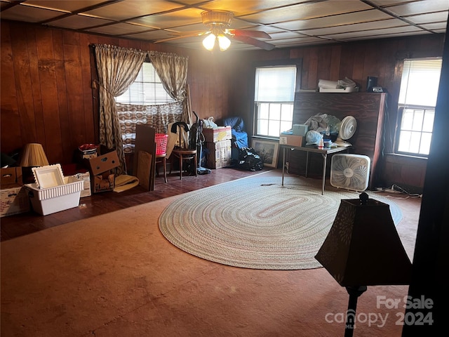 living area featuring ceiling fan and wood walls