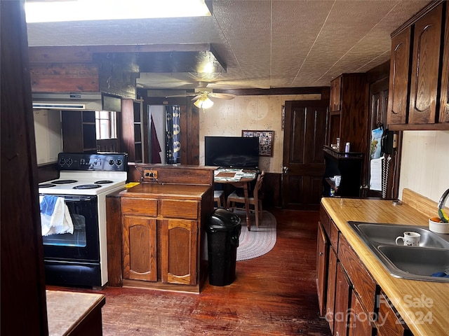 kitchen with dark wood-type flooring, sink, wood walls, ceiling fan, and electric range