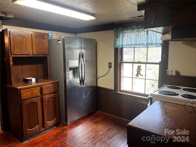 kitchen featuring exhaust hood, stainless steel fridge, wooden walls, dark wood-type flooring, and white range with electric cooktop