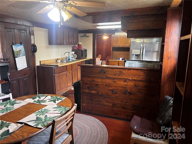 kitchen with ceiling fan, kitchen peninsula, sink, dark hardwood / wood-style flooring, and stainless steel fridge