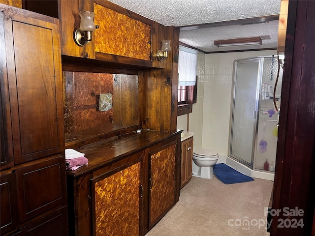 bathroom with a textured ceiling, toilet, a shower with door, and vanity